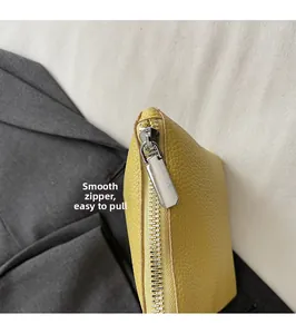Macro shot of smooth silver metal zipper and lychee texture on yellow leather bucket bag