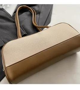Detailed view of bicolor patchwork tote with woven texture and leather handle on desk