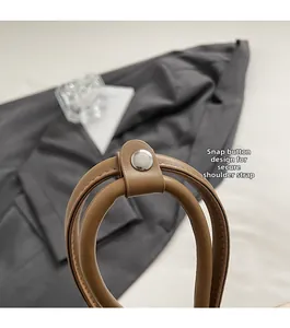 Macro shot of leather shoulder strap with silver snap button on a brown bowling bag