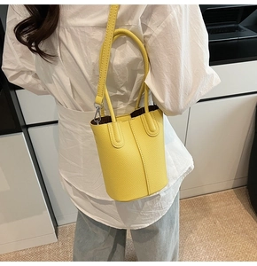 Detailed shot of yellow bucket bag with lychee grain leather and dual ring handles