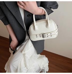 Détail du sac Boston blanc crème avec doubles ceintures décoratives et boucles métal