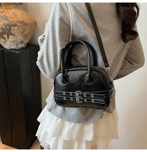 Vue portée d'un sac Boston noir brillant avec détails de sangles à œillets punk