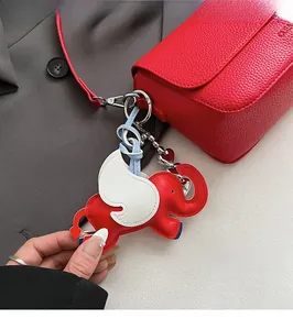 Close-up of a red elephant leather keychain with heart charm on a square handbag