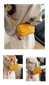 Détail du sac à bandoulière jaune motif litchi avec chaîne en métal et breloque éléphant