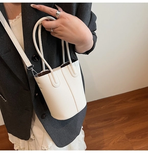 Detail of white lychee grain leather bucket bag with top handle and detachable strap