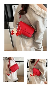 Détail du sac rouge en cuir grainé avec un charme d'éléphant et des finitions argent