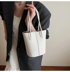 Detailed view of white lychee leather bucket bag showing vertical stitching and texture