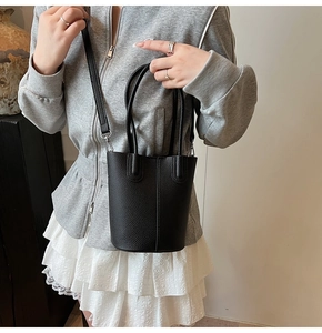 Detail of black lychee grain leather bucket bag with silver hardware and shoulder strap