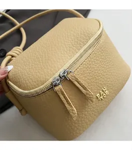 Dettaglio borsa beige in pelle martellata con doppia cerniera e tracolla con nodo