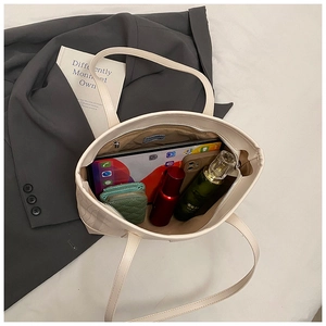 Detailansicht der cremefarbenen Ledertasche zeigt geräumigen Innenraum und Alltagsgegenstände.