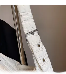 Detail of white quilted nylon bag showing wide shoulder strap and silver metal buckle