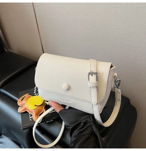 Detail of off-white lychee texture square bag with elephant charm and brand logo