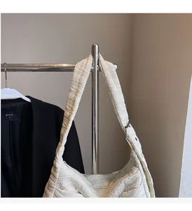Detail of cream quilted tote bag showing wave stitching texture and adjustable metal buckle