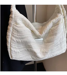 Detail of white quilted puffy shoulder bag featuring a soft wavy pattern and metal tag
