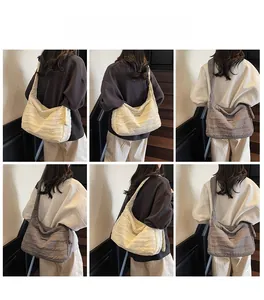 Detail view of large quilted crossbody bag with pleated texture in beige and grey