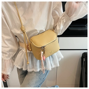 Dettaglio borsa a scatola in pelle litchi beige con pendente a cuore e nappa lunga