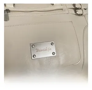 Close-up of white leather handbag featuring silver zippers and hardware with logo plate