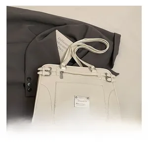 Close-up of cream faux leather handbag with buckle details and metal logo plate