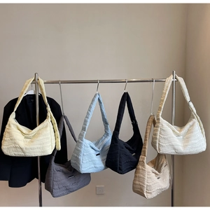 Row of colorful quilted nylon tote bags hanging with wide adjustable shoulder straps