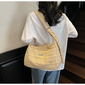 Close-up of beige quilted tote bag with wavy texture and adjustable wide shoulder strap