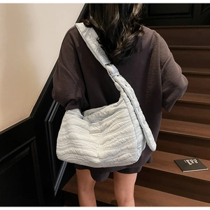 Detail of the sky blue quilted puffer bag with wide adjustable strap on shoulder