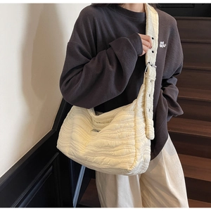 Detail view of cream quilted tote bag with wave pattern and wide adjustable shoulder strap
