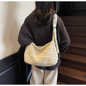 Detail of cream quilted tote bag showing wave texture and adjustable wide strap