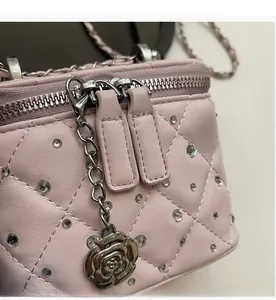 Dettaglio borsa a tracolla trapuntata rosa con ciondolo a rosa d'argento e doppia zip