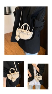 Detail of lychee pattern leather saddle bag with heart charm and metal twist lock