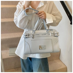 Detail of light blue faux leather handbag featuring silver buckles and outer zipper pocket