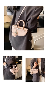 Pink faux leather saddle bag detail with metal lock and heart charm on a mini shoulder bag