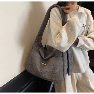 Close-up of grey quilted puffer hobo bag with wide shoulder strap on model side view