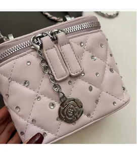 Dettaglio borsa a tracolla trapuntata rosa con strass e ciondolo a forma di camelia