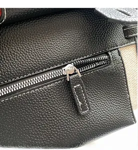 Close-up of smooth silver zipper and white stitching on black lychee grain leather bag