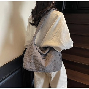 Détail d'un grand sac cabas matelassé gris foncé avec bandoulière large et surpiqûres