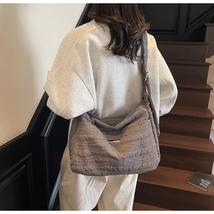 Détail de la texture matelassée et plaque métallique sur le grand sac cabas gris