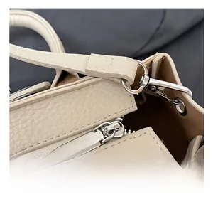 Detail of silver-tone hardware D-ring and hook on beige lychee pattern leather bag