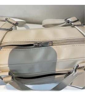 Detail view of the silver metal zipper and stitching on a cream large hobo shoulder bag