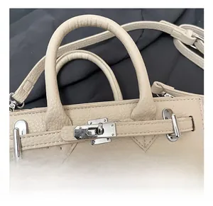 Macro detail of beige lychee grain texture and silver metal rotating lock on saddle bag