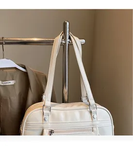 Detailed view of cream PU messenger bag showing silver zippers and double handles