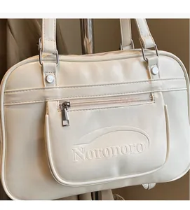 Macro shot of cream messenger bag showing Noronoro logo texture and silver rivets