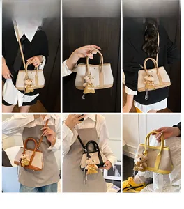Model display of canvas bucket bag with leather trim and teddy bear pendant