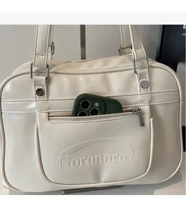 Close-up of cream messenger bag showing functional front zipper pocket for phone storage