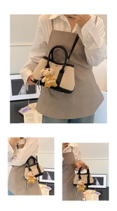 Detail of canvas bucket bag with contrast leather trim and cute bear charm accessory