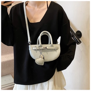 Detail of lychee pattern leather saddle bag with silver twist lock and heart charm