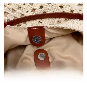 Close-up of woven tote bag featuring silver magnetic buckle and brown leather strap