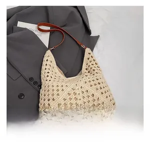 Detail showing beige hollow-out crochet texture and brown leather shoulder strap on tote bag
