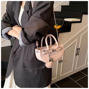 Detail of a pink saddle bag with lychee texture and heart charm in a lifestyle setting