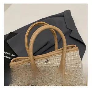 Close-up of canvas bucket bag with brown leather trim and metallic magnetic closure