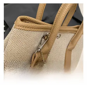 Detail of off-white canvas bucket bag with brown leather trim and silver metal hook